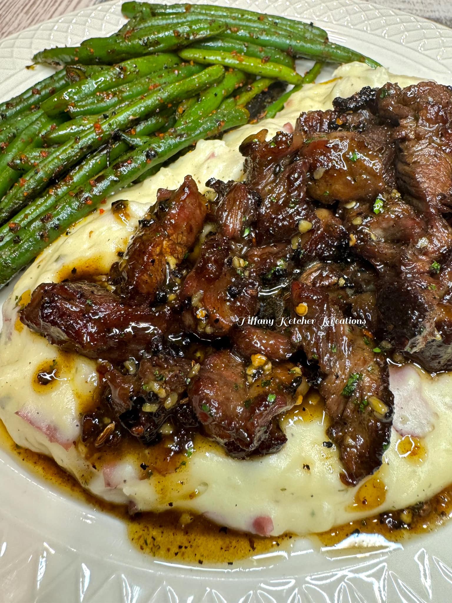 Garlic butter steak bites over creamy aged white cheddar mash with green beans